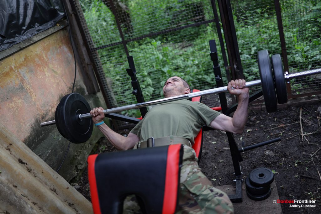 Donbas Frontliner, Ukraine war, artillery grad Partizan, Aidar battalion, soldier do sport. There’s also a sports ground and a barbell. Someone is always lifting it. Good physical condition is important in war.
