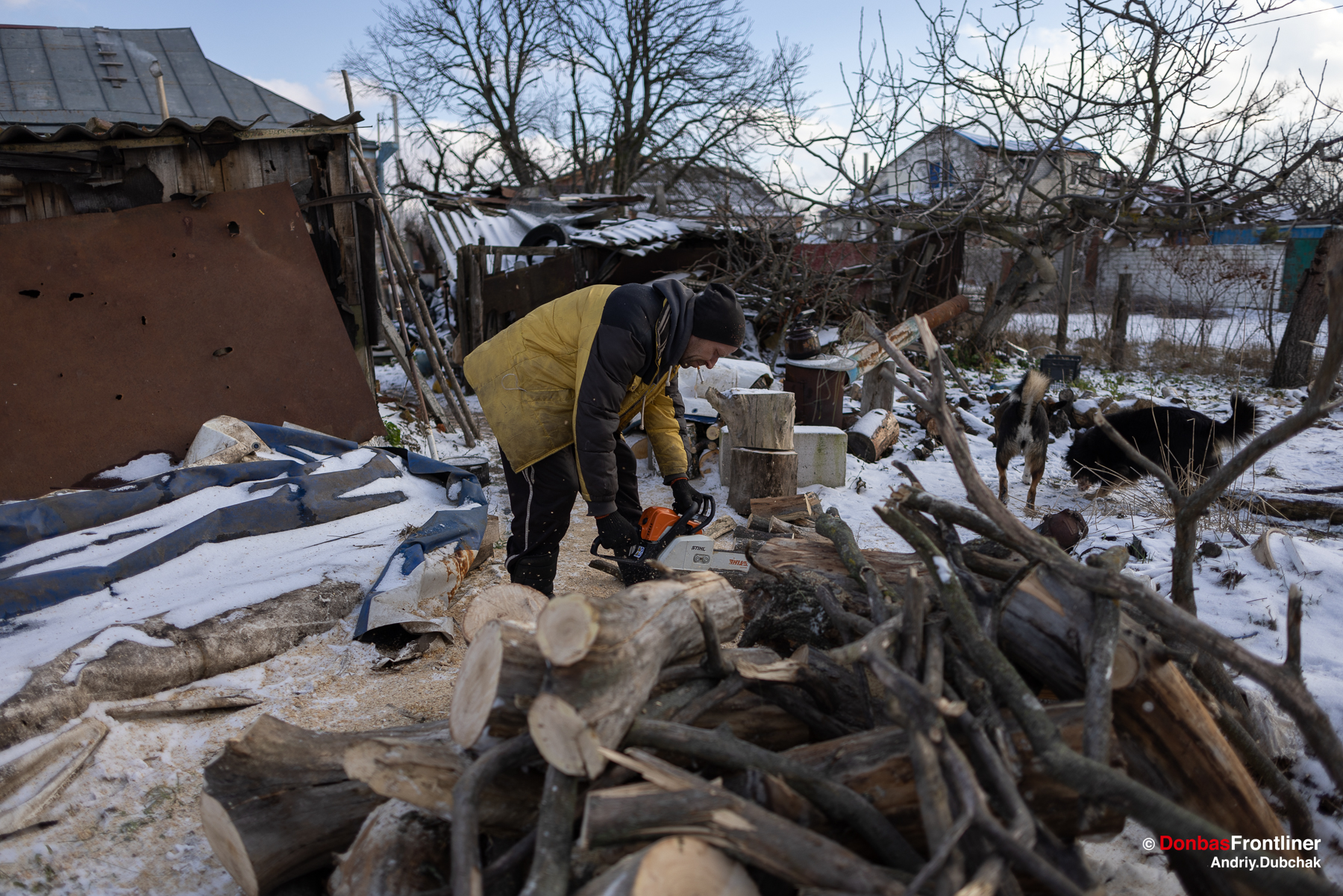 Чоловік ріже дрова біля розбитого будинку у селі Руські Тишки
