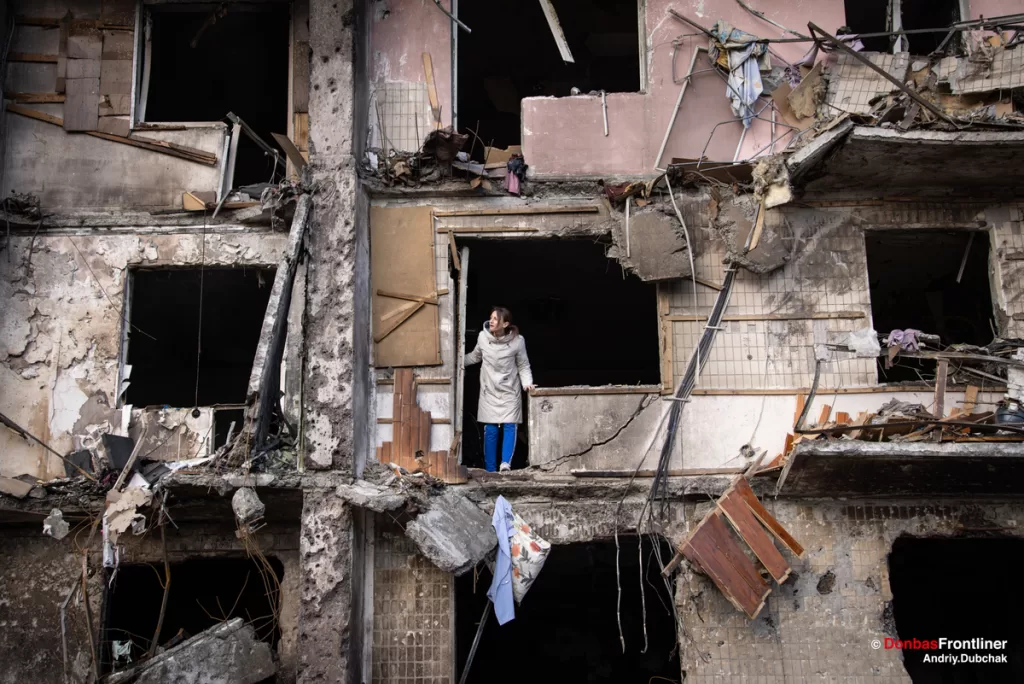 Жінка виглядає з квартири зруйнованої вибухом російської ракети по вулиці Кошиця 7а у Деснянському районі, Київ, 25 лютого 2022 року.