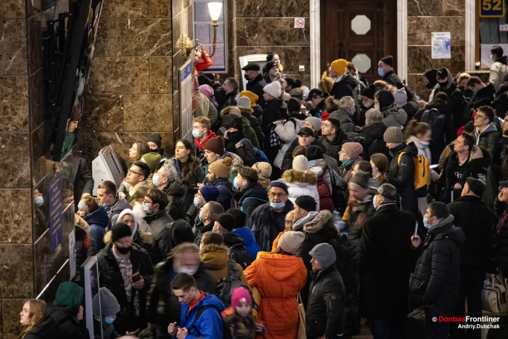 Черга біженців перед табло з розкладом руху та затримок поїздів на Центральному залізничному вокзалі Києва, 25 лютого 2022 року.