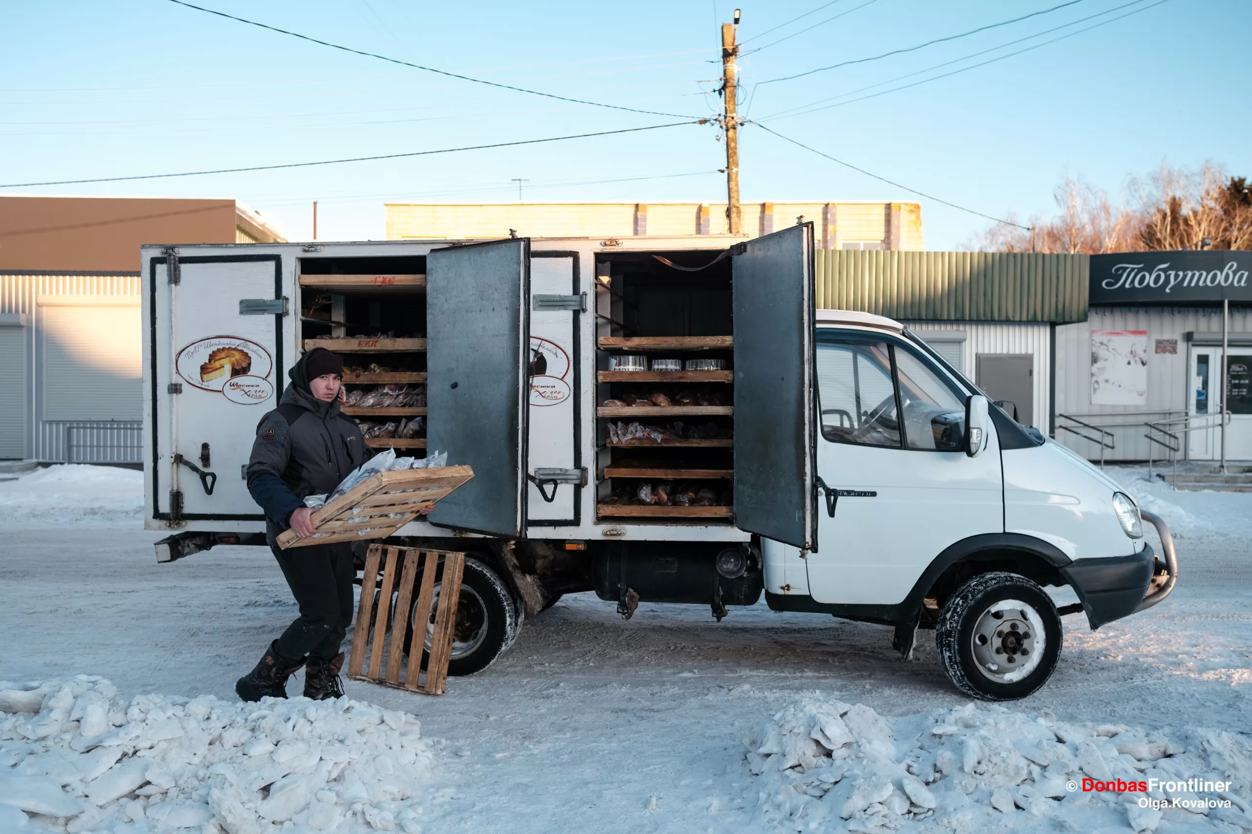 Місцевий мешканець розвантажує машину з хлібом, який привезли з сусіднього міста на продаж. Ямпіль, Сумська область, Україна, 17 січня 2024 року.
